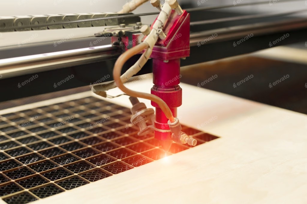 Close-up of a laser cutting head engraving a pattern into wood