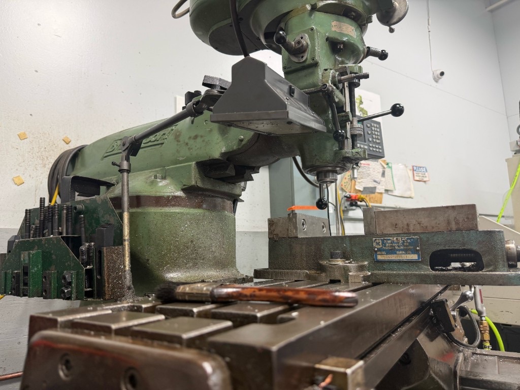 Green Bridgeport milling machine with a Kurt vise on the work table