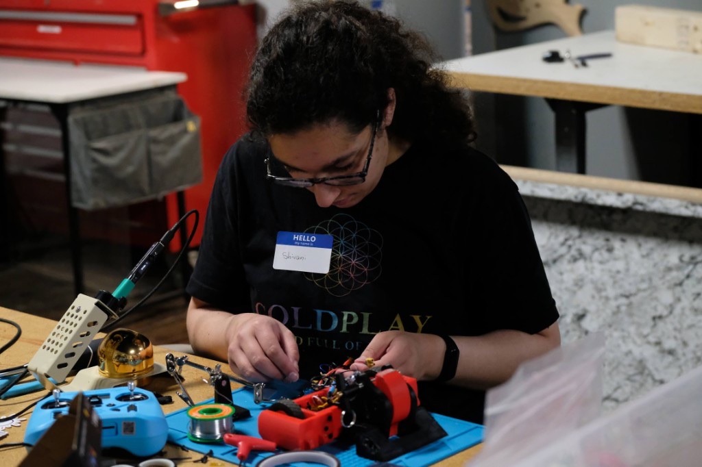Maker soldering and wiring a small robotics project on a workbench
