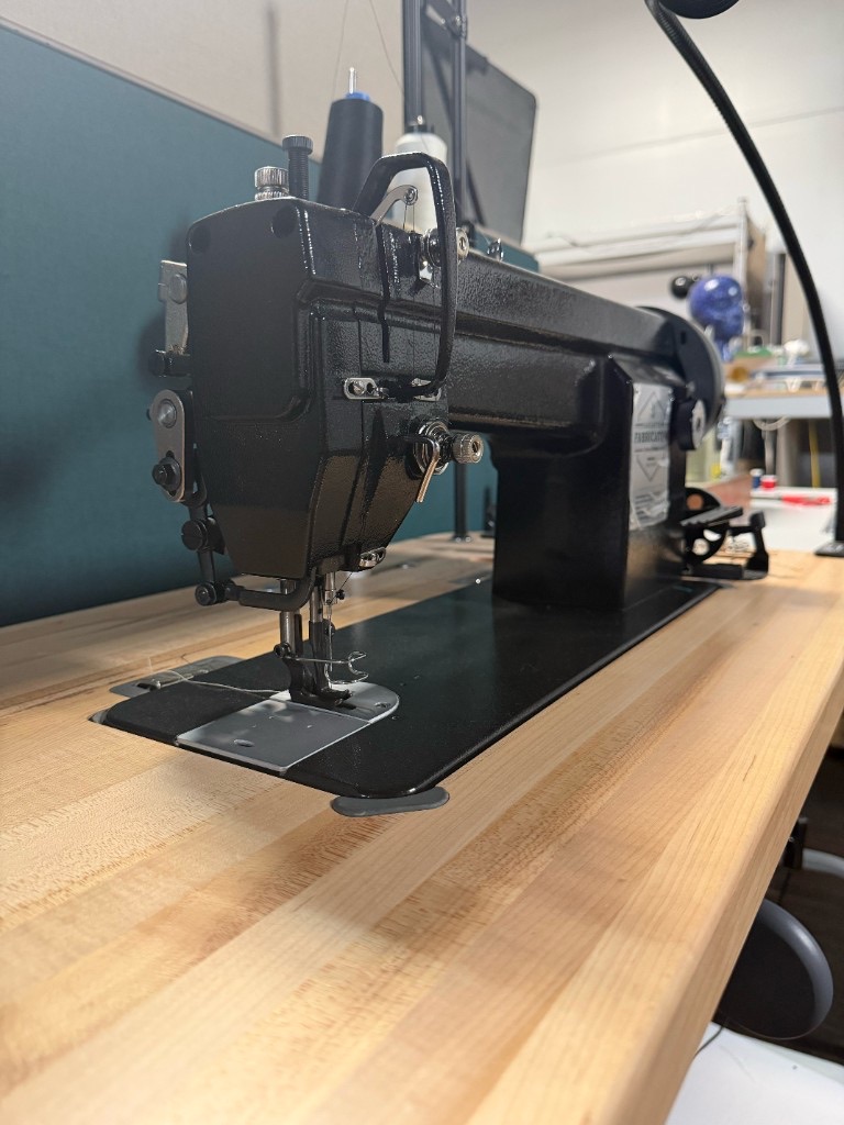 Industrial sewing machine set into a wood workbench in the fiber arts area