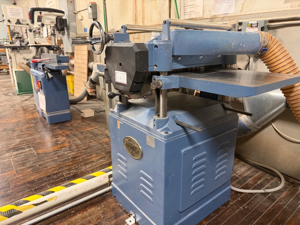 Blue Oliver thickness planer in the wood shop with dust collection hose attached