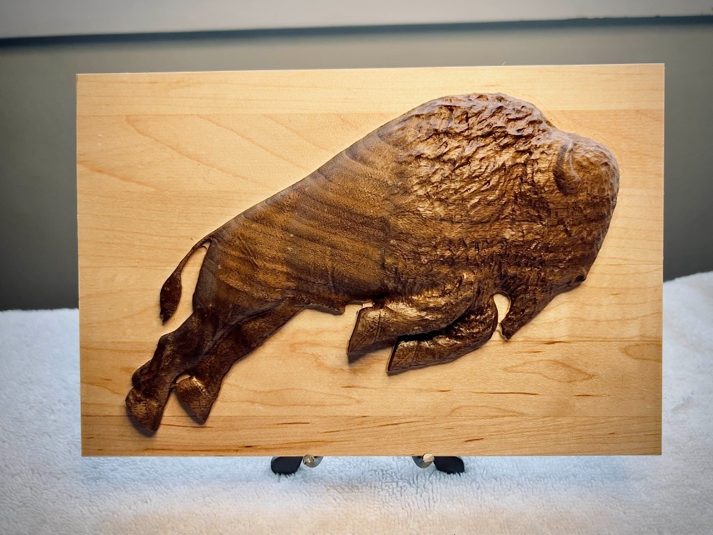 Carved bison relief on a wooden plaque